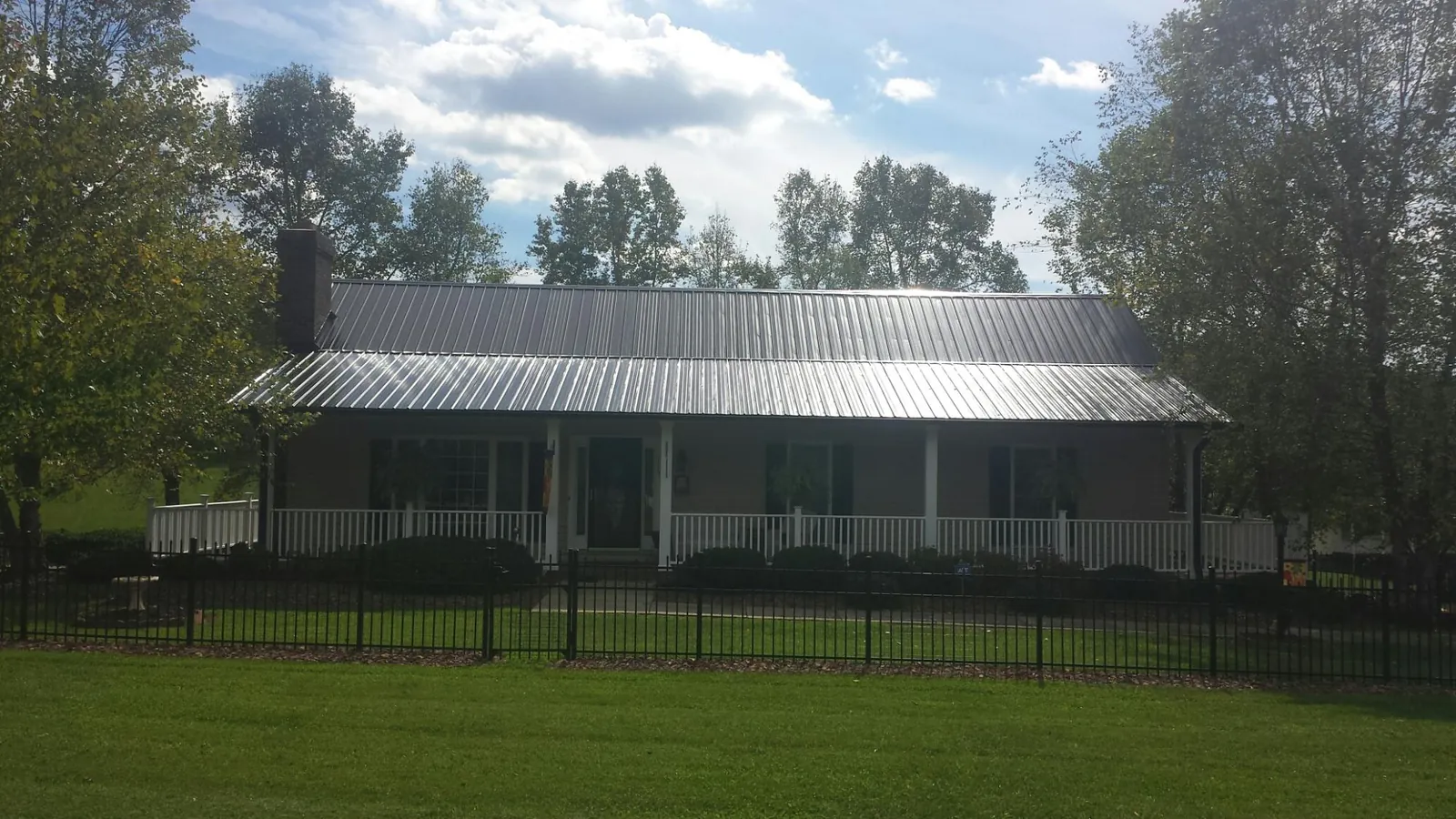 Gray metal roof on a brick ranch with a full width front porch — Gutter Guard Installation work by our crew in Monticello
